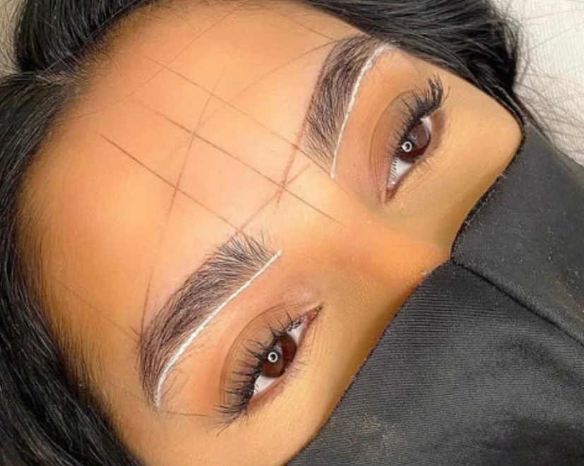 Technician measuring brow arch proportions using string eyebrow mapping technique
