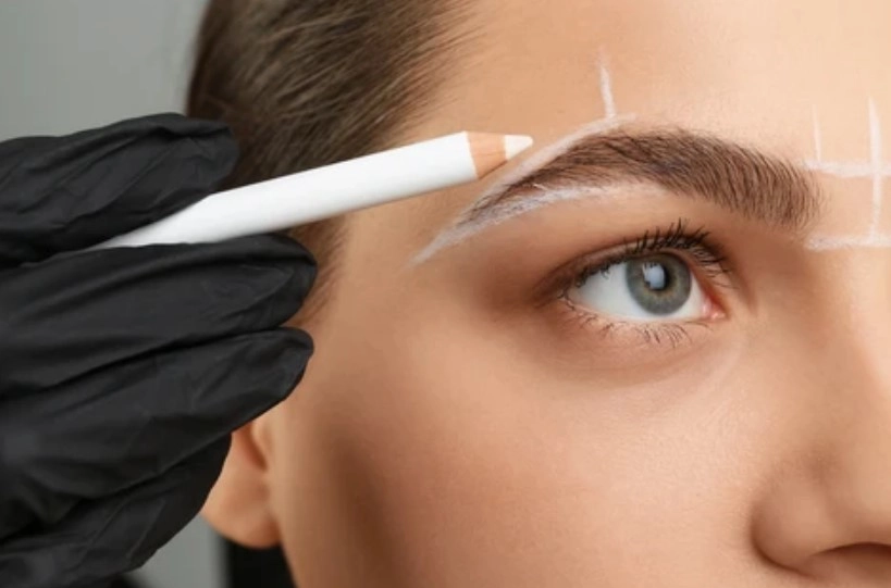 Precision eyebrow mapping outline drawn with white pencil for facial symmetry