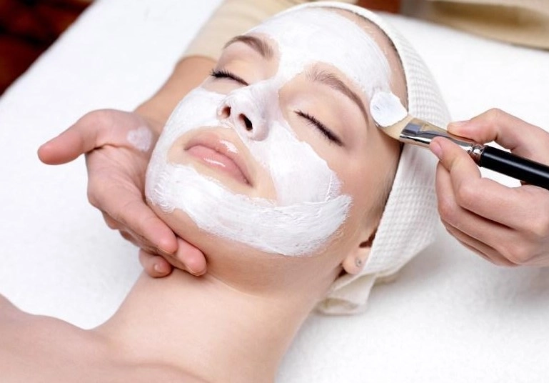 Esthetician applying hydrating organic facial cream mask for dry skin