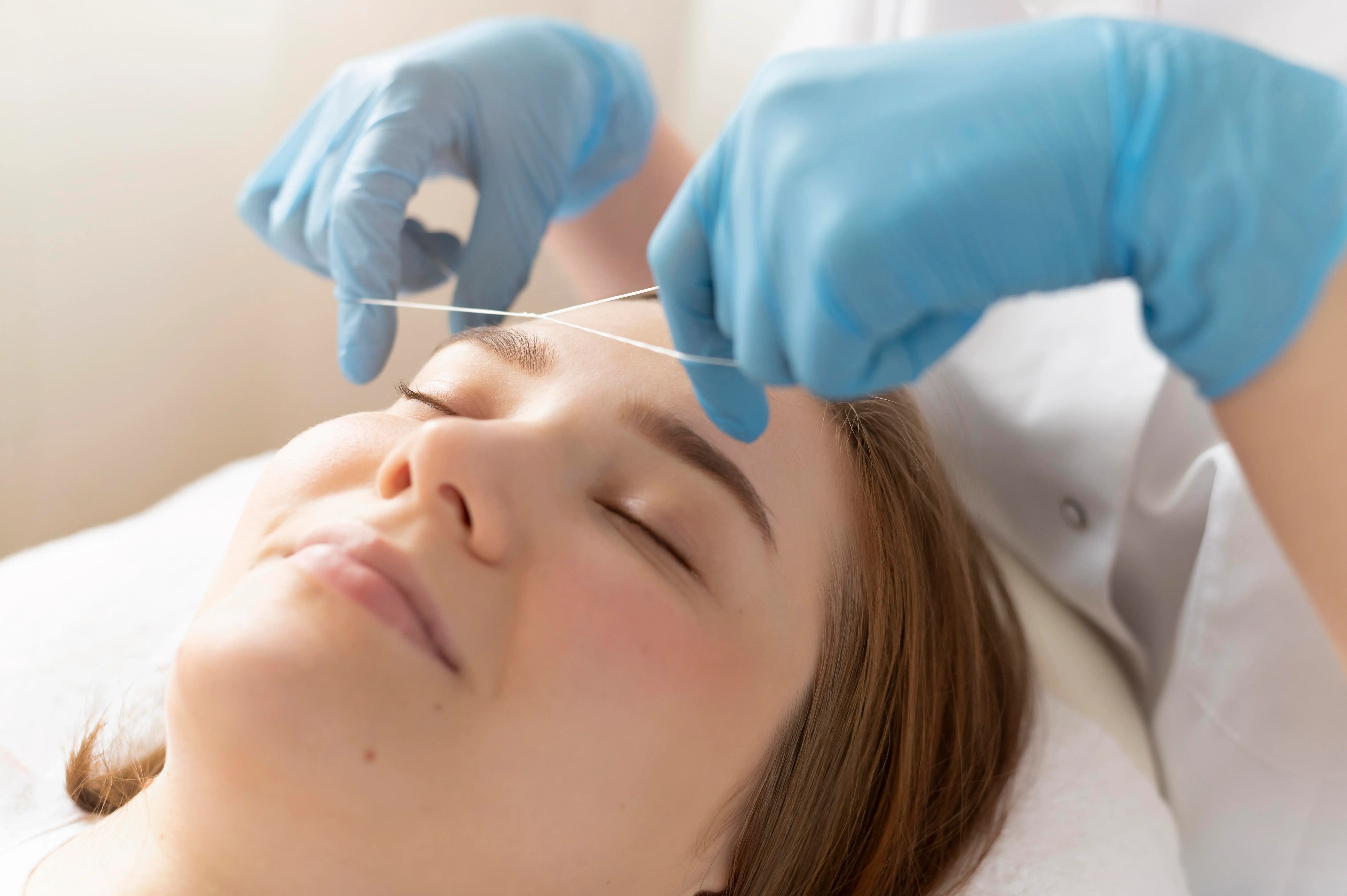 Skilled esthetician expertly threading a client's eyebrows in a chic Woodside salon, highlighting precision and comfort